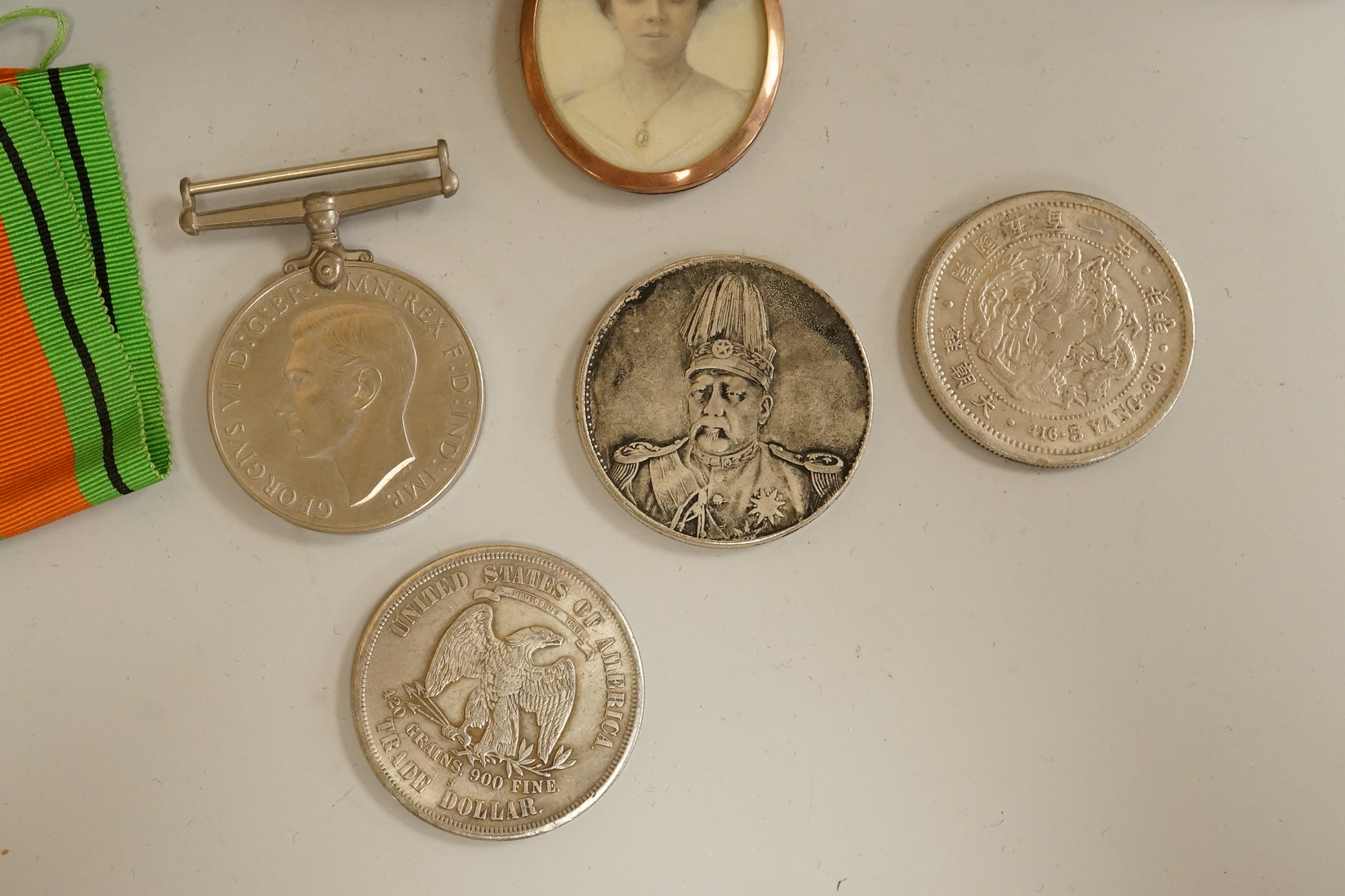 A large cloisonné enamel box containing a cast mask handle, an oval hair pendant, coins and medals, etc.